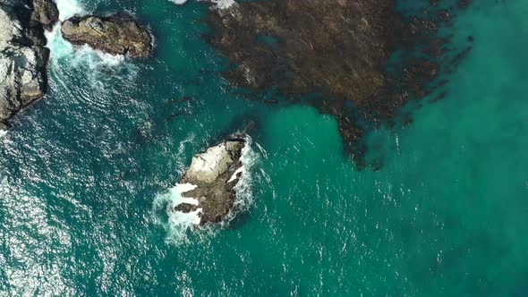 Aerial drone top down view flying left revealing the Pacific rocky coast along the cliffs of Big Sur
