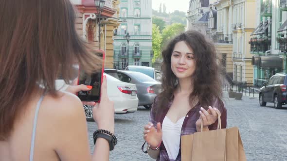 Cheerful Young Woman with Shopping Bags Posing for a Photo for Her Friend