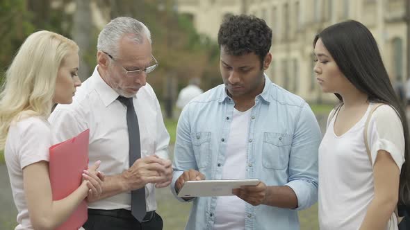 Students showing tablet PC presentation to their teacher, discussing project