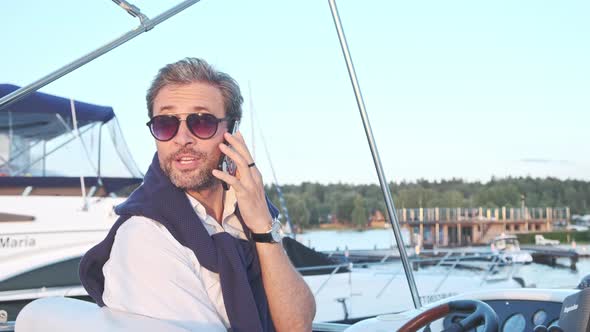 Handsome Successful Man on the Yacht Talking on Mobile Phone. Portrait of Business Man on Sailing