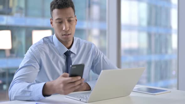 African American Businessman Using Cellphone in Office