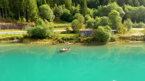 A boat on a beautiful lake with a shed on the banks