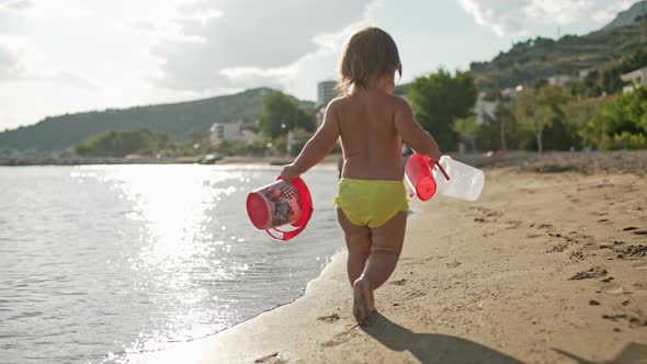 Baby Girl Plays on the Sandy Beach Plays with Toys Near the Sea