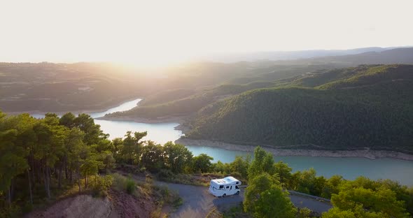 Drone flying forwards revealing a caravan parked with incredible views of a blue and turquoise lake