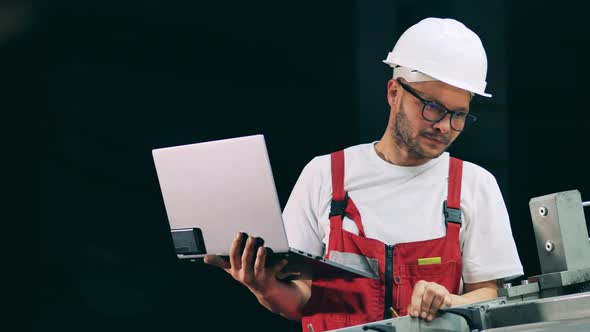 Engineering Specialist with a Laptop is Observing a Conveyor