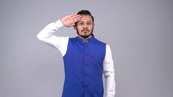 Proud Indian man saluting to the camera in an Indian outfit