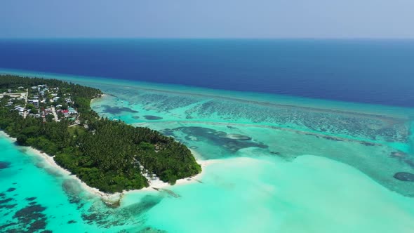 Aerial flying over panorama of idyllic tourist beach vacation by turquoise ocean with white sand bac