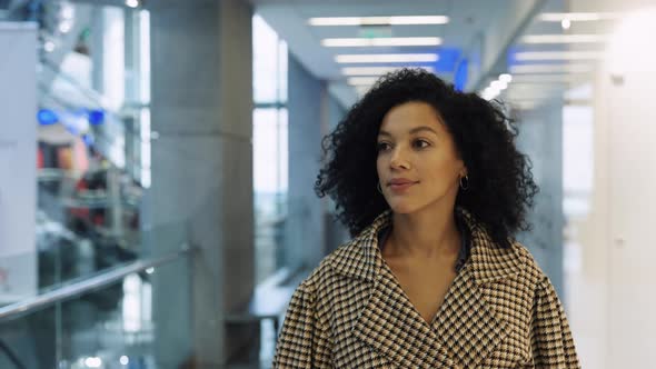 Happy African American Woman Walks Around Mall Past at Shop Windows with Branded Clothing