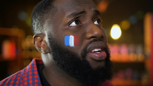 Black French Football Supporter With Flag on Cheek Unhappy With Team Failure