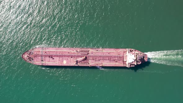 Aerial top down view of a red oil tanker floats.