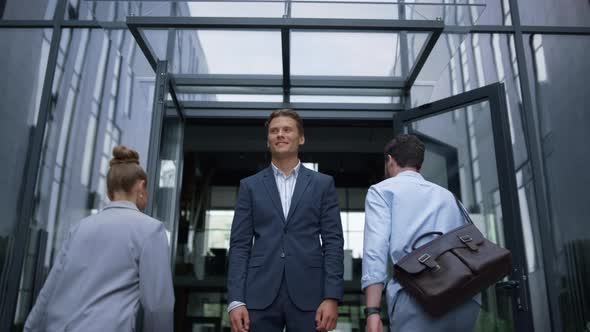 Happy Businessman Standing at Office Door Meeting Joyful Workers