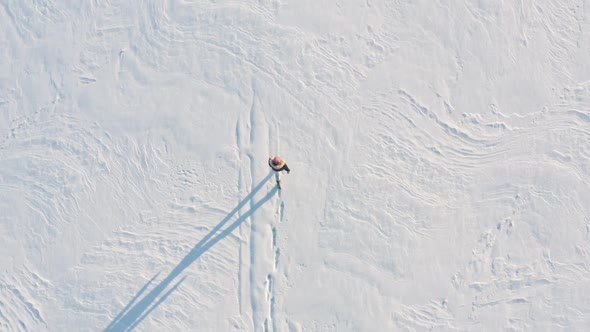 Man Walking on a Snowy Field