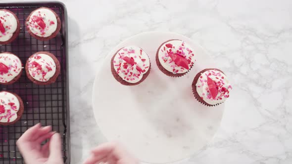 Flat lay. Step by step. Decorating red velvet cupcakes with sprinkles and chocolate hearts and kisse