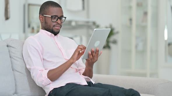 Relaxed African Man Using Digital Tablet at Home