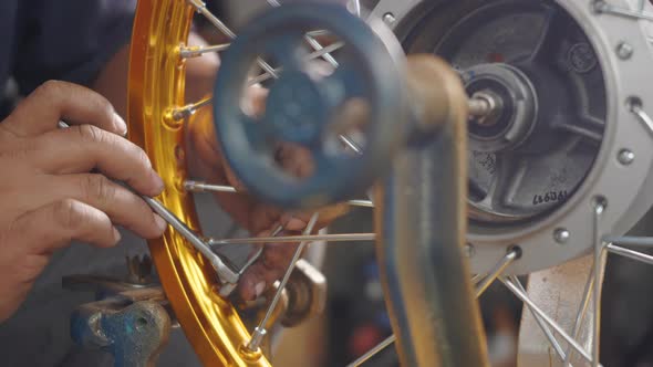 Technician man working motorcycle wheel has spokes weave up on mechanic tool new steel wheel