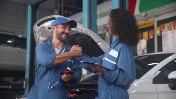 Team of mechanic with man and woman holding tablet computer in uniform talking and handshake.