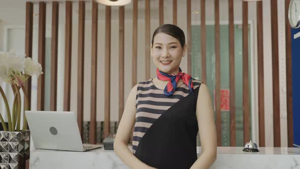 hotel receptionist is standing in front of the hotel lobby with a smile of congratulations