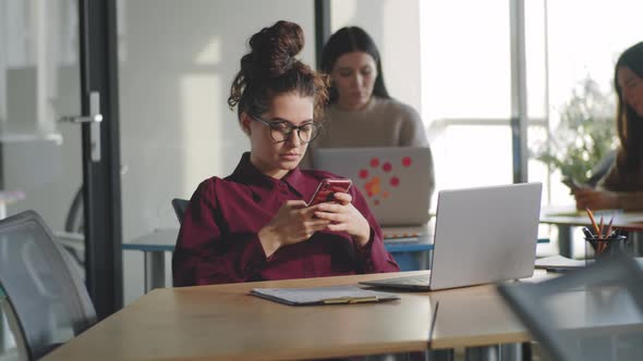 Female Office Worker Using Smartphone at Desk