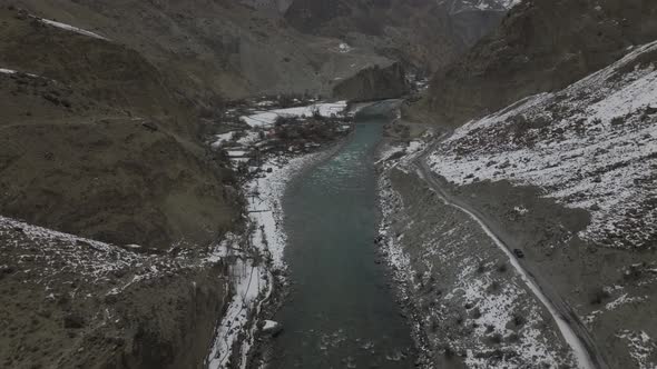 Aerial Flying Over Hunza River With Black Truck Driving Along Road Through Remote Rugged Landscape V