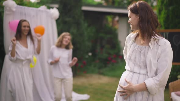 Portrait of Happy Redhead Caucasian Pregnant Woman Caressing Belly in Slow Motion with Blurred