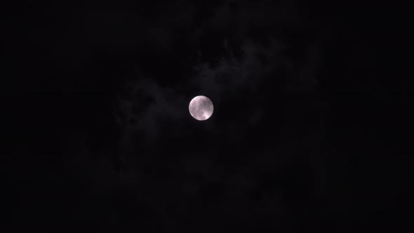 Bright Full Moon Behind Fast Moving Dark Clouds on Night Sky