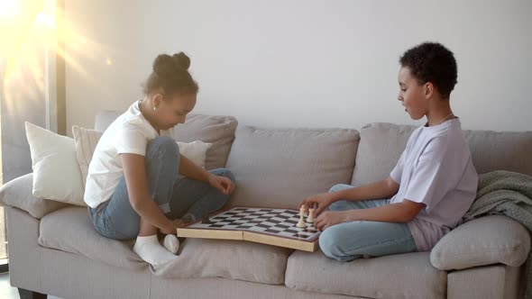 African American Brother and Sister Playing Chess on Couch at Living Room