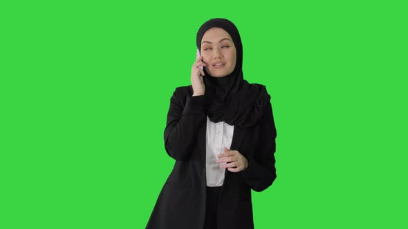 Arabic Business Woman Wearing Hijab Speaking on the Phone on a Green Screen, Chroma Key.