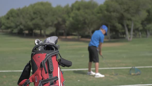 Chico practica golf en un campo. Bolsa con palos de golf. Slowmotion