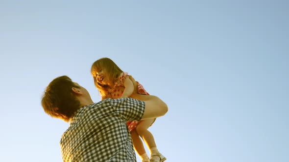 Concept of Happy Family. Dad Throws Baby Up High Against Sky. Dad Plays with His Little Daughter