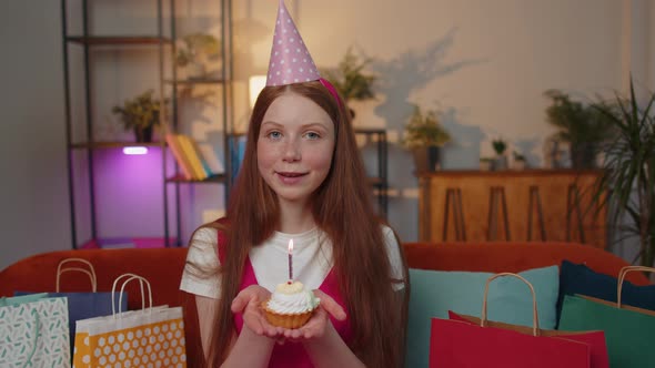 Happy Child Girl Kid Celebrating Birthday Party Makes Wish Blowing Burning Candle on Small Cupcake