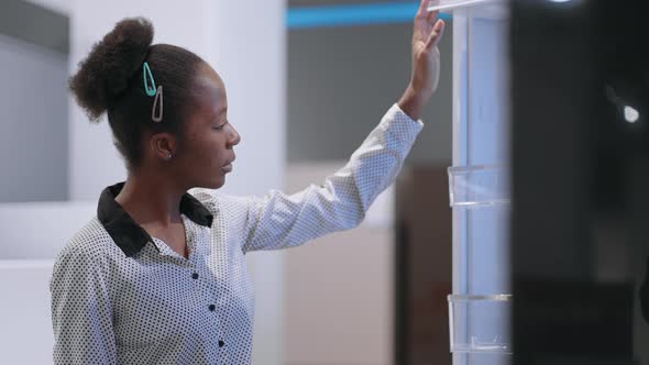 Black Woman is Choosing Refrigerator in Home Appliance Store Viewing Exhibition Sample Inside