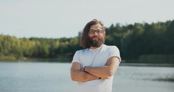 A Portrait of a Man with Long Hair and Beard Glasses on His Nose a Boy Puts Arms Crossed Looks Into