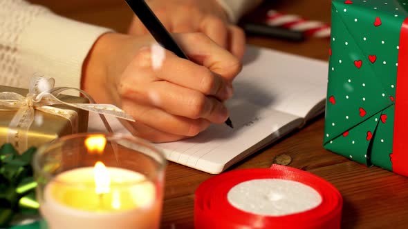 Female's Hands Writing Letter To Santa in Notebook