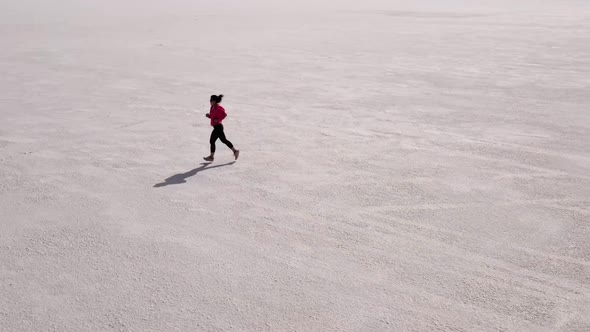 Aerial shot of an Asian woman jogging across the Bonneville Salt Flats flats