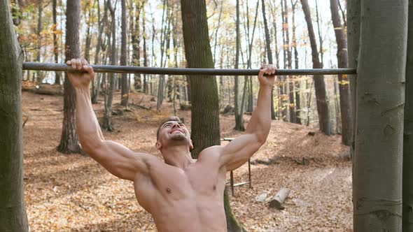 Strong Naked Guy Pulls Up On Pole. Exercise Emphasizes All The Muscles Of The Man.