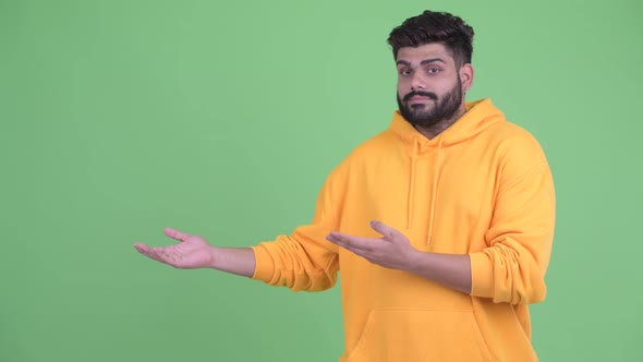 Stressed Young Overweight Bearded Indian Man Showing Something