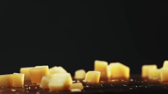 Cubes of Delicious Cheese Fall Down Onto Table on Black