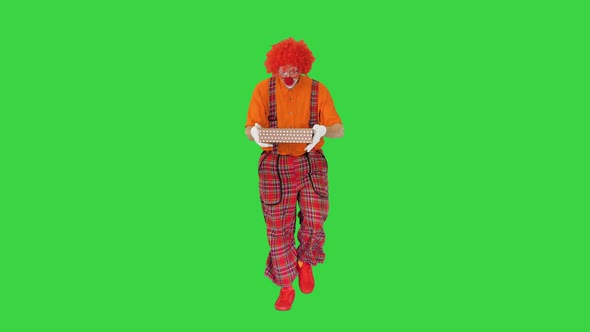 Male Clown Carrying a Present on a Green Screen Chroma Key