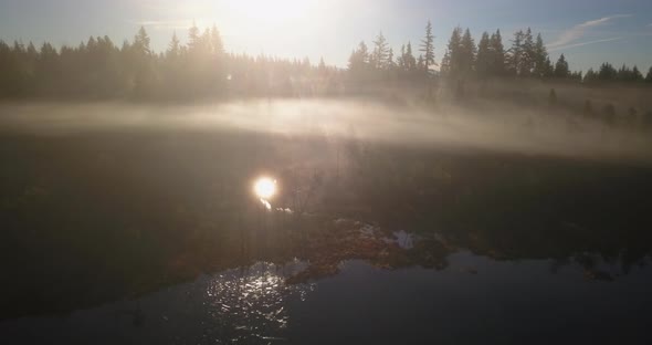 Aerial view of Sunbeam reflections shining through mist over lake