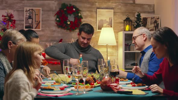 Adult Man Opening a Bottle of Wine Sitting at the Table