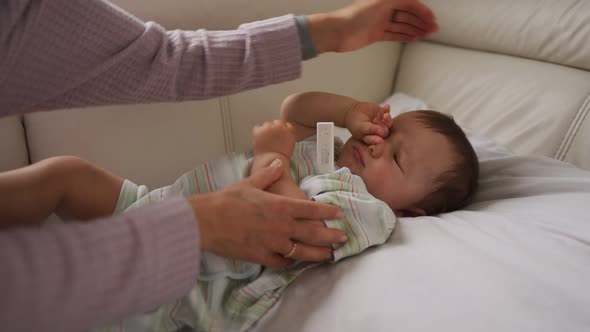 Mother Measuring Temperature of Her Ill Kid at Background