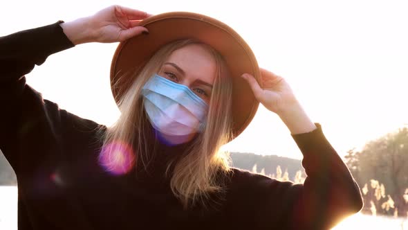 Caucasian Blonde Woman with Beige Hat in Black Sweater Wear Protective Mask in the Countryside
