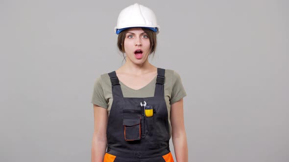 Portrait of Shocked or Outraged Woman Builder in Helmet and Jumpsuit Shaking Head in Rejection While