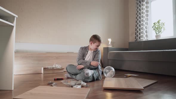 Boy Sits on Floor Among Details of Furniture Shows Handle to Domestic Hamster