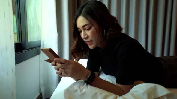 slow-motion of woman using smartphone on a bed