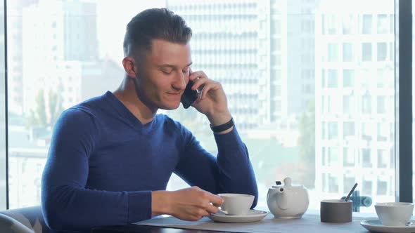 Man Enjoying Drinking Tea and Talking on the Phone at the Restaurant