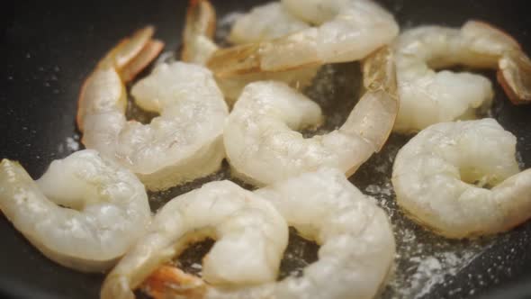 Unrecognizable cook frying prawns in pan with hot oil