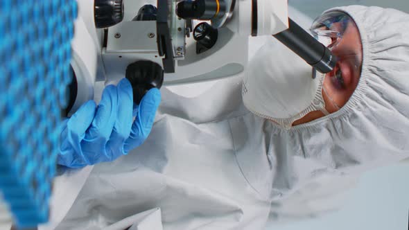 Vertical Video Scientist Wearing Ppe Suit Looking at Samples Under Microscope