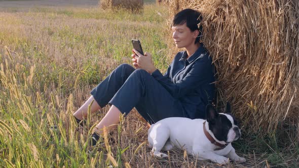 Girl with Dog Resting Messaging on Smartphone Outdoors