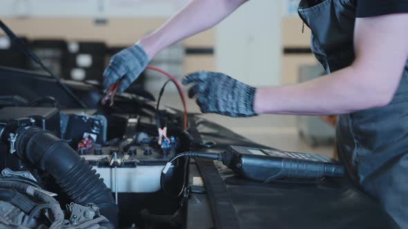 A Mechanic at a Car Service Station Checking the Battery